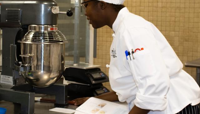 A culinary student working with a commercial mixer