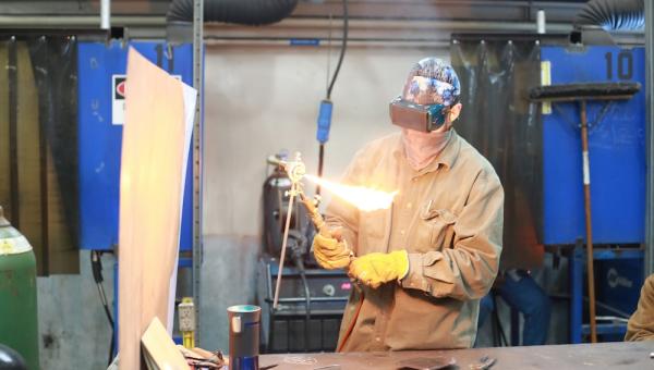 a welding student working in the workshop with a torch