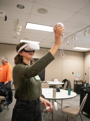 a student using a VR headset smiles as they reach up