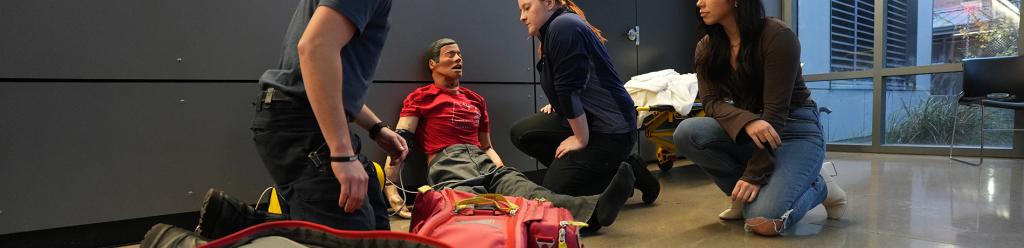 EMT students, one man and two women, practicing with a dummy in the Health Professions building
