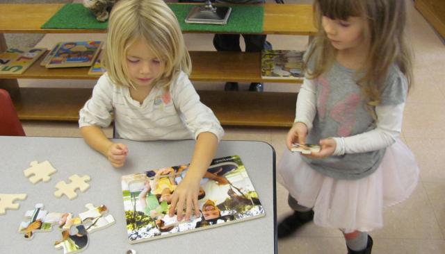 Kids putting together a puzzle.