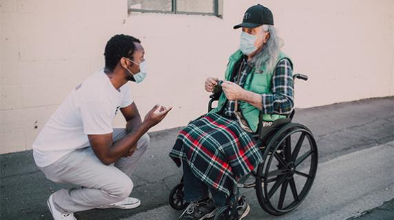 man helping another man in a wheelchair