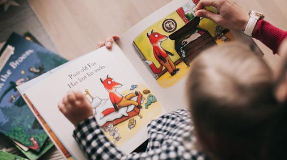 overhead view of baby reading a picture book with a fox