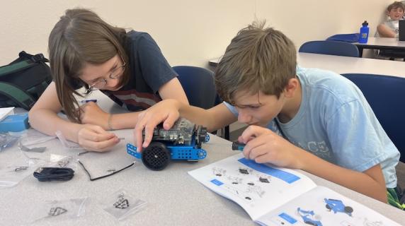 two high schoolers work build and program a robot together at computer summer camp