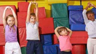 four kids of different ages reaching up and stretching