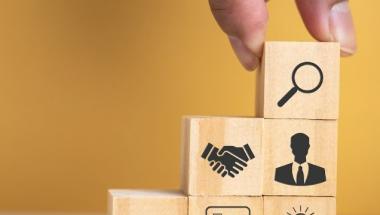 hand putting wood blocks with business icons into a staircase formation