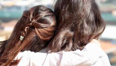 backview of daughter hugging mother at the beach