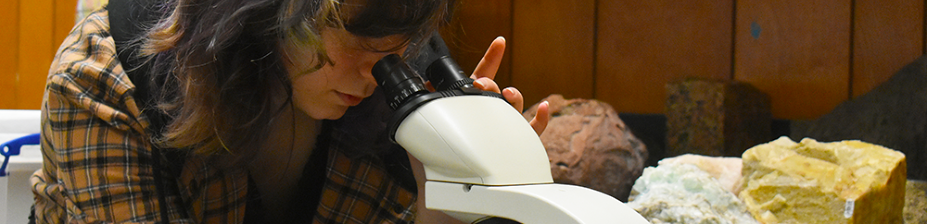 student in geology lab looking through microscope