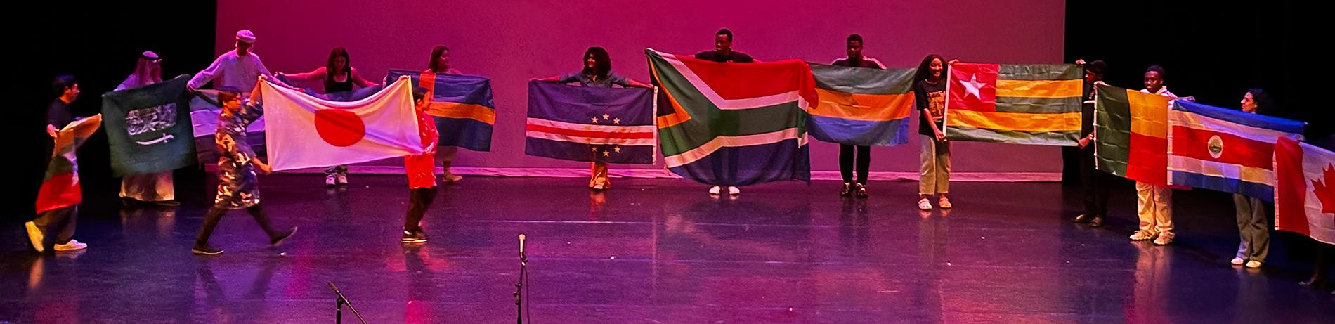 international students on stage holding up their respective flags