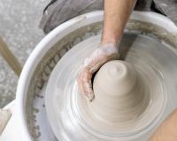 hands working clay on a pottery wheel