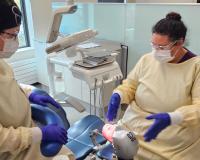dental assisting students in scrubs and masks learn on a training dummy in the new LCC dental clinic