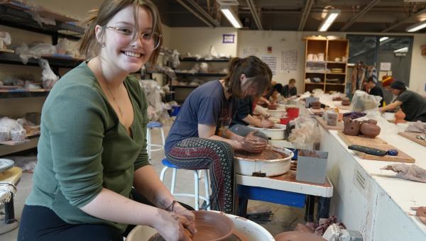 art student throwing clay at a wheel