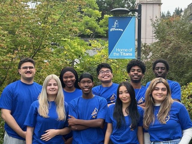 a diverse group of students smiling and standing under an LCC flag