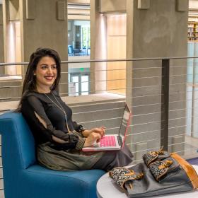 a fashionable student smiling as she studies in the library