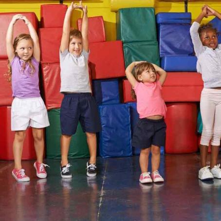 four kids of different ages reaching up and stretching