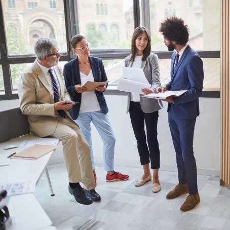 group of four business people standing and discussing