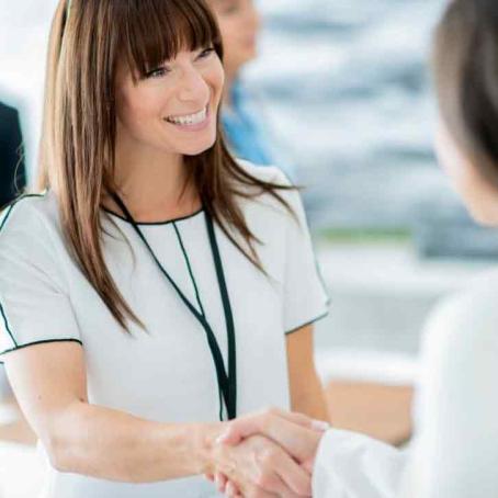 smiling woman shaking hands with another person