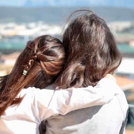 backview of daughter hugging mother at the beach