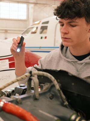 aviation maintenance student inspects an airplane engine